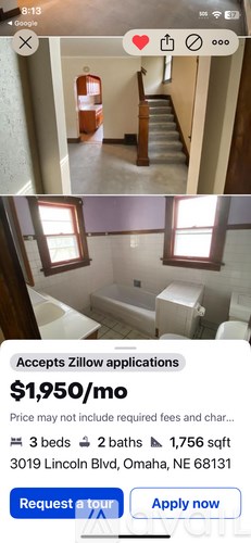 A room with a bed and a window showing the interior of a house.