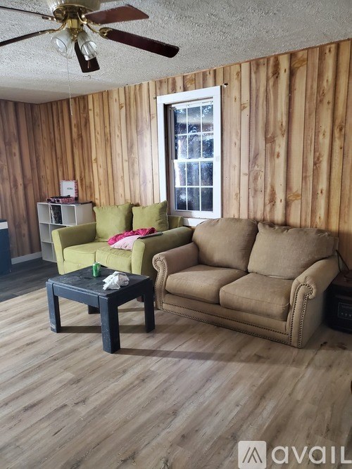 A living room with a brown couch, a green chair, and a black coffee table.