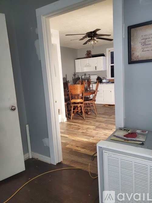 A room with a ceiling fan and a dining table with chairs.