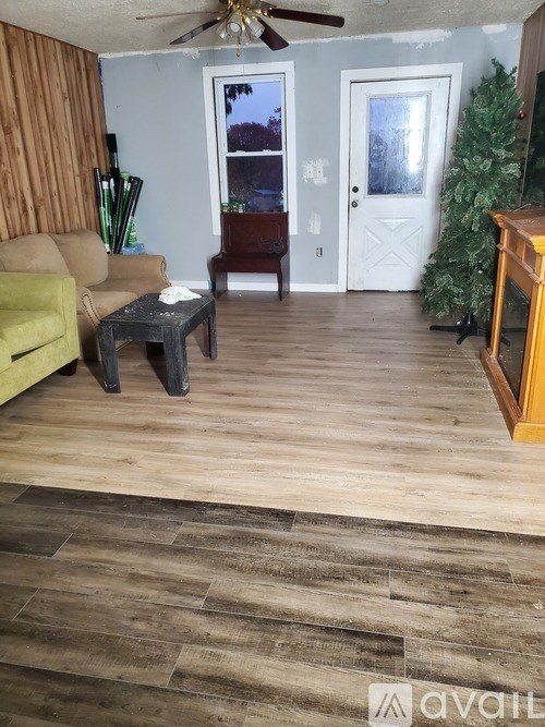 A living room with a yellow couch, a coffee table, and a ceiling fan.
