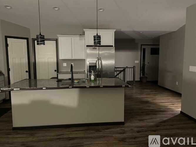 A modern kitchen with a center island and pendant lights.