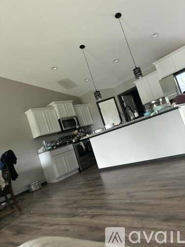 A kitchen with white cabinets and a wooden floor.