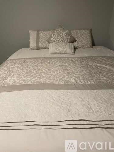 A bed with a white comforter and four pillows.