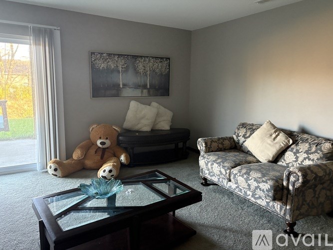 A living room with a couch, a coffee table, and a teddy bear.