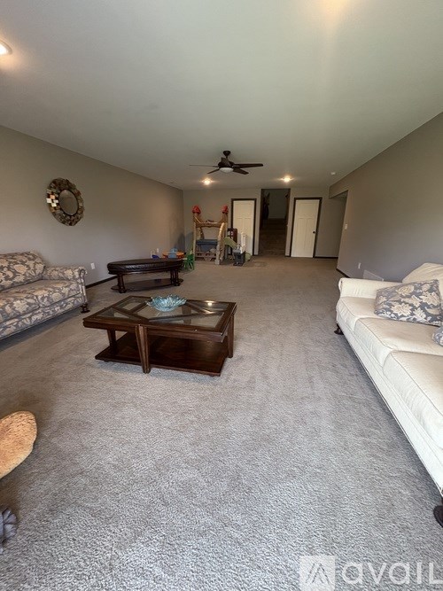 A living room with a couch, coffee table, and a ceiling fan.