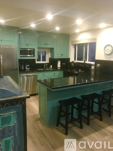 A kitchen with a black counter top and wooden bar stools.