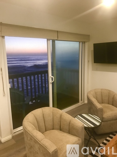 A living room with a view of the ocean through a sliding glass door.
