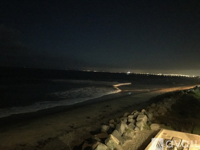 A beach at night with lights from the buildings in the distance.