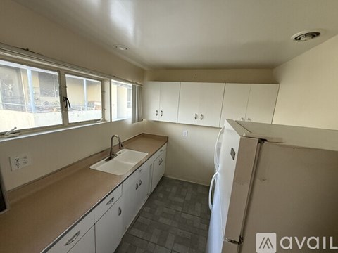 A kitchen with white cabinets and a white refrigerator.