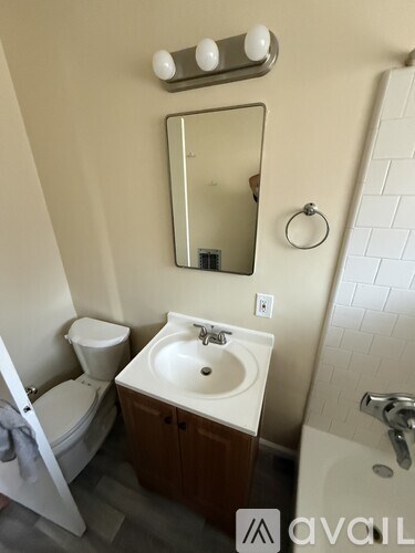 A bathroom with a sink, toilet, mirror and a ring light.
