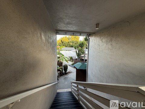 A narrow alley with a metal railing on the right side.