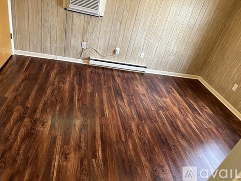 A room with wooden flooring and a wall-mounted air conditioner.