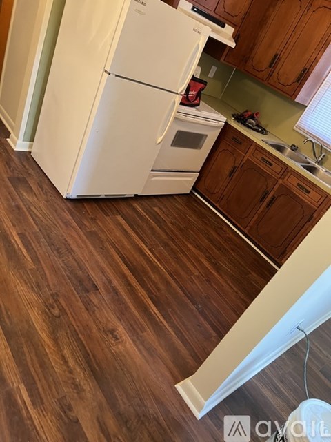 A white fridge and oven in a kitchen with wooden floors.