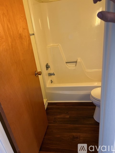 A bathroom with a wooden door and a white bathtub.