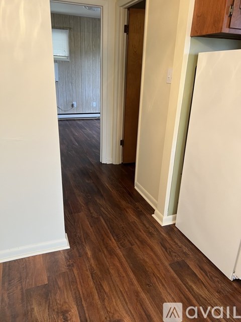 A hallway with wood floors and white walls.