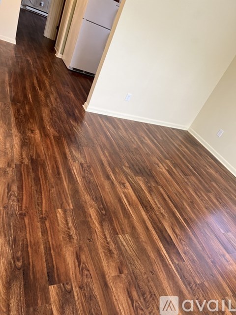 A kitchen with a white fridge and wooden floors.
