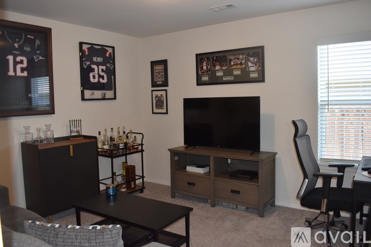 A living room with a TV, a chair, and a cabinet with bottles on it.