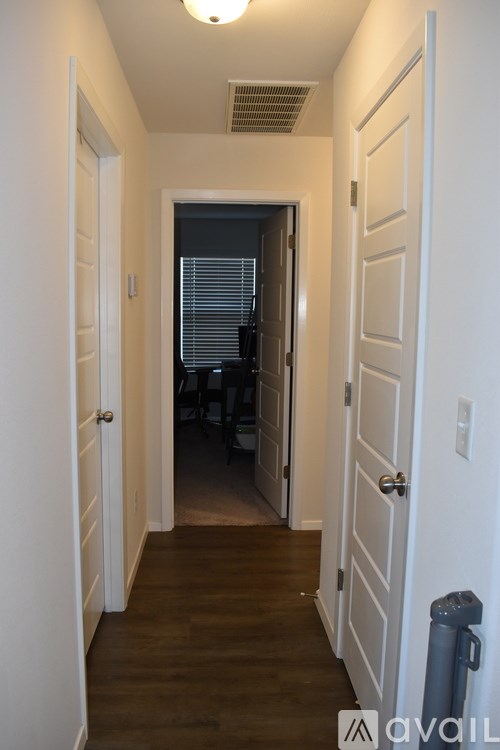 A hallway with white doors and a trash can.