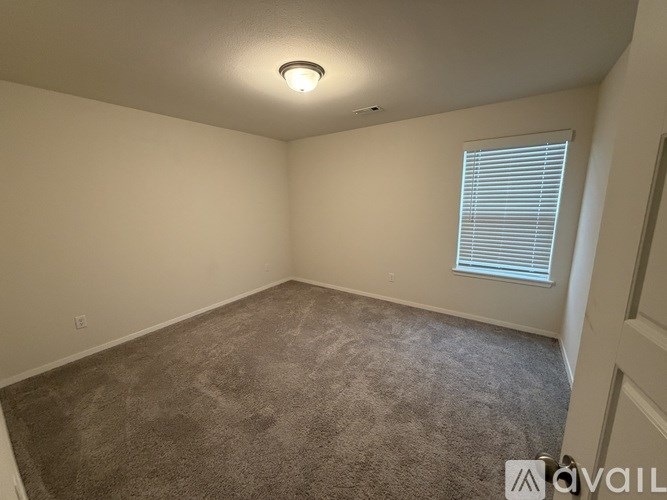 A room with a carpeted floor and a window with blinds.