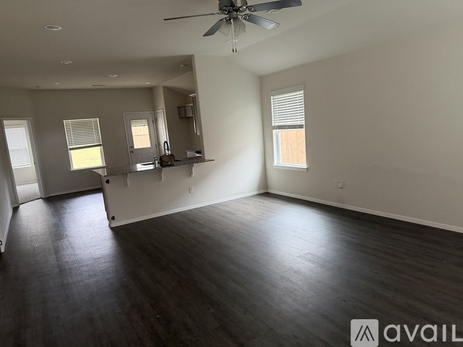 A spacious room with a ceiling fan and wooden flooring.
