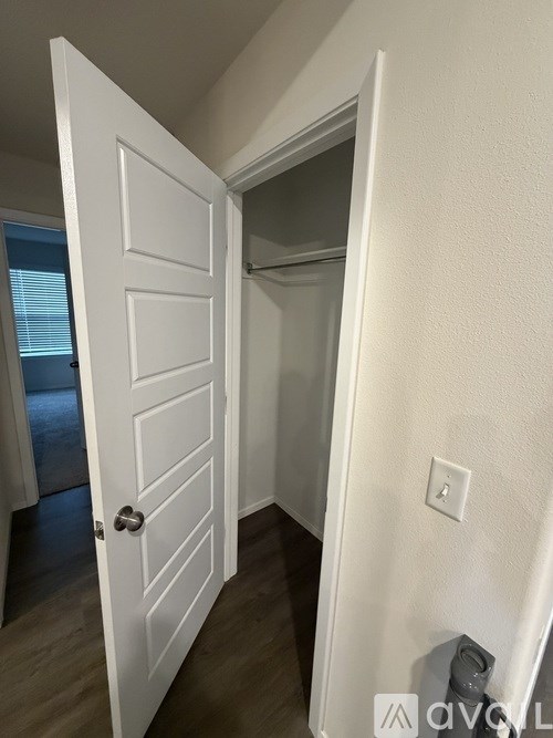 A white door is open to a room with a white wall and a light switch.