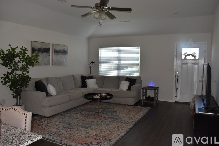 A living room with a couch, a chair, a coffee table, and a ceiling fan.
