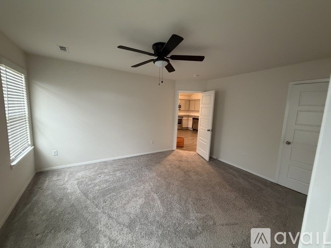 A room with a ceiling fan and carpeted floor.