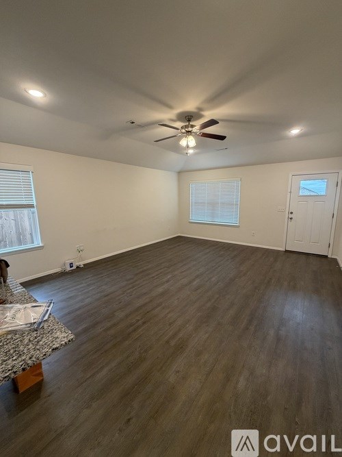 A room with a ceiling fan and wooden flooring.
