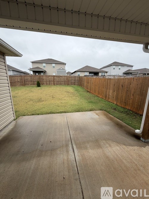 A backyard with a concrete patio and a wooden fence.