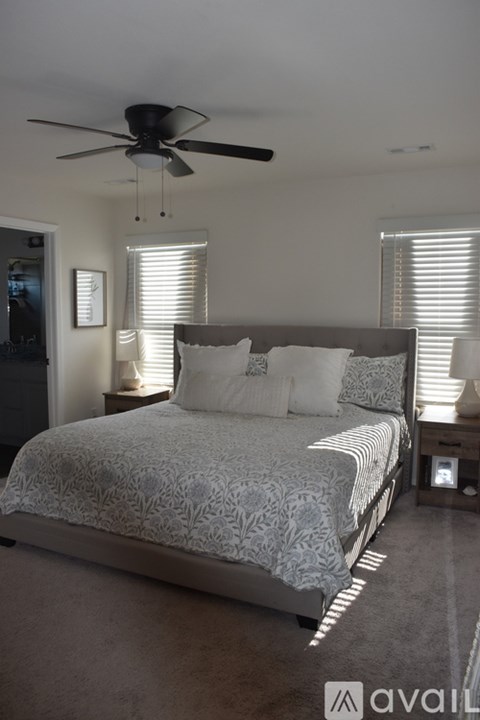 A bedroom with a large bed and a ceiling fan.