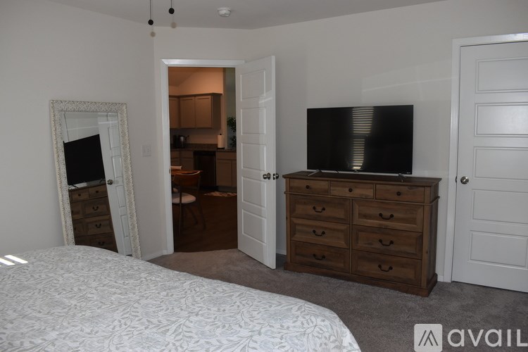 A bedroom with a large bed, a dresser, and a mirror.