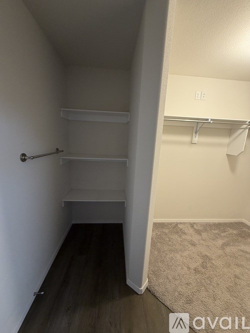 A small, empty room with a door on the left and a shelf on the right.