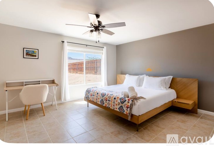 A bedroom with a bed, chair, and window.