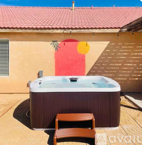 A hot tub sits on a patio with a wooden chair in front of it.