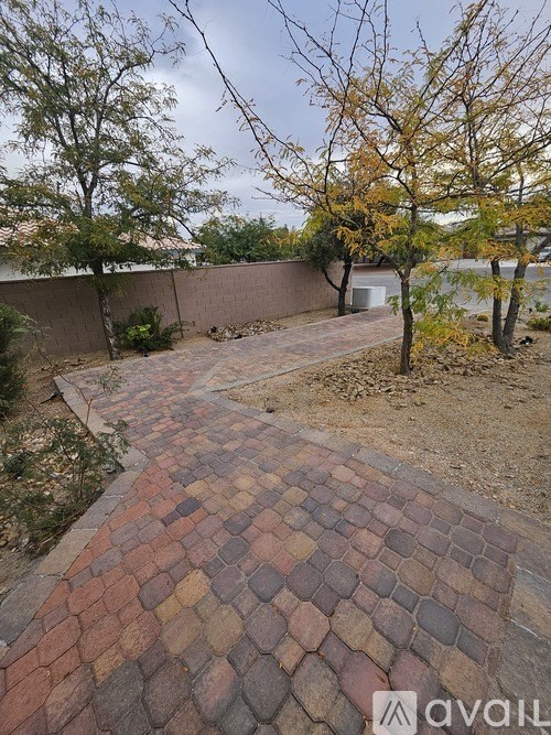 A backyard with a brick pathway and a tree.