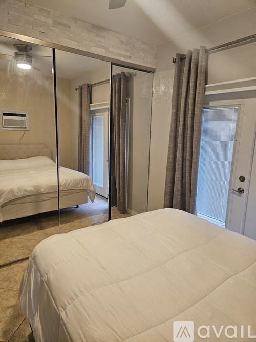 A bedroom with a large bed and a mirrored wall.