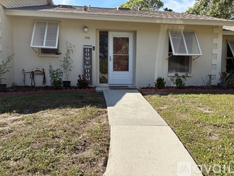 A white house with a brown roof and a white door.