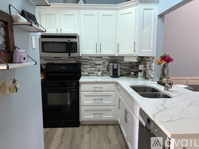 A kitchen with black appliances and white cabinets.