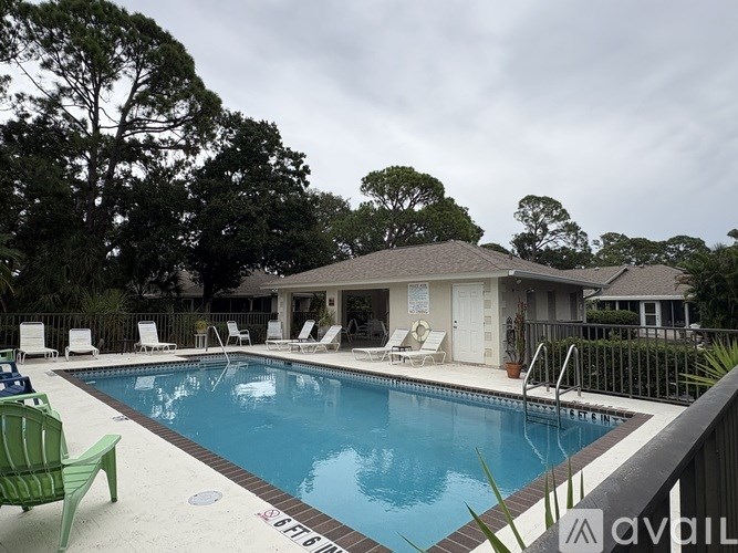 A pool with a green chair and a house in the background.