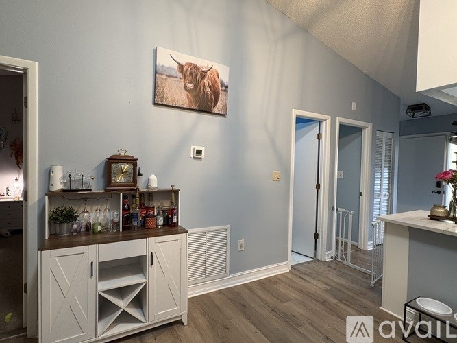A room with a grey cabinet and a painting of a cow on the wall.