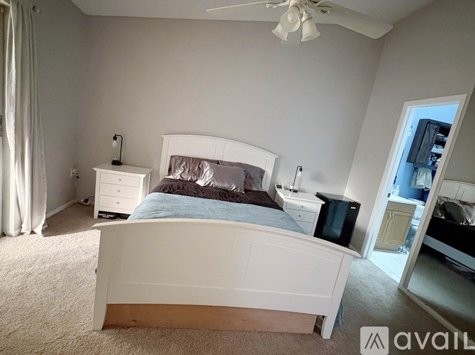 A bedroom with a large bed, a white dresser, and a ceiling fan.