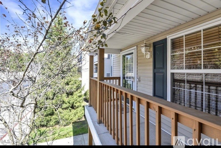 A balcony with a view of trees and a house.