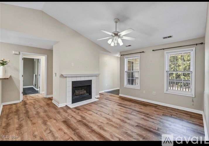 A living room with a fireplace and a ceiling fan.