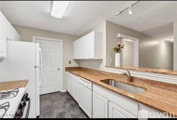 A kitchen with white cabinets and a wooden countertop.