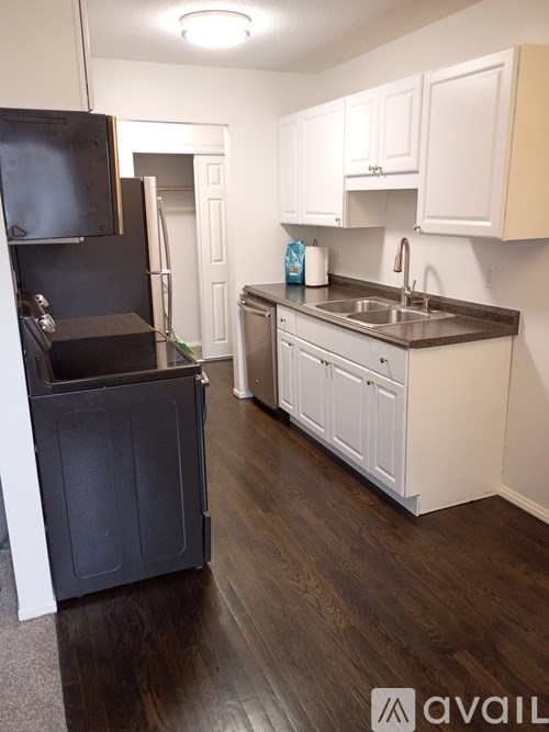 A kitchen with white cabinets and a black fridge.