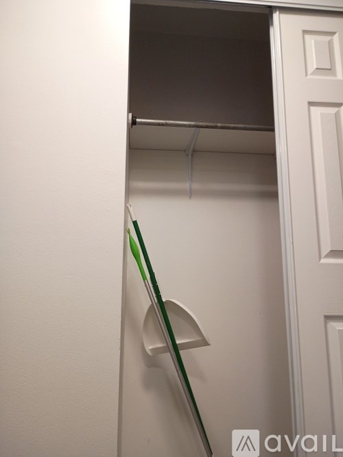 A white closet with a green broom leaning against it.