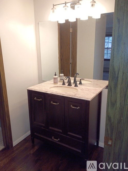 A bathroom vanity with a marble countertop and a mirror above it.