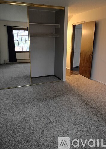 A room with a grey carpet and a window with black curtains.