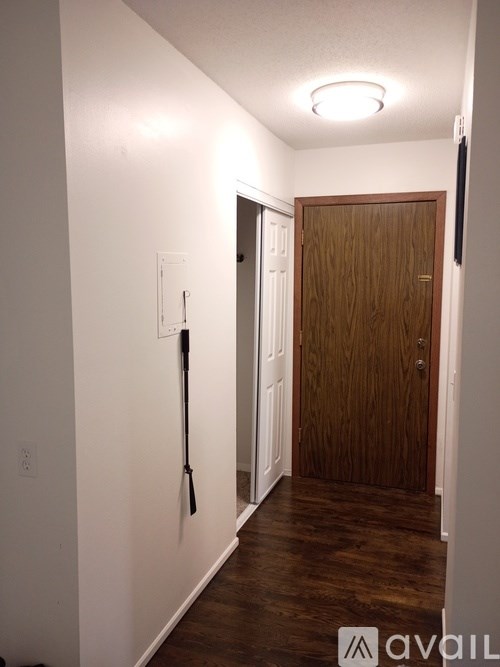 A hallway with a wooden door and a white wall.
