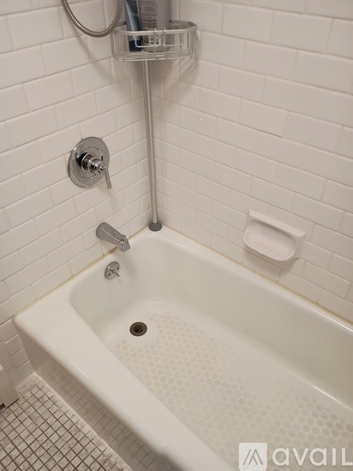 A white bathtub with a shower head and a drain in the middle.